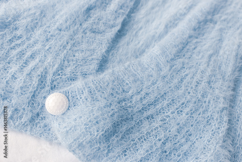 Obraz na płótnie Blue knitted cardigan with white button on white background. Soft blue knitted sweater in details. Knitting pattern background. Summer knitted fashion. Cozy hobby. Craft product concept. w salonie