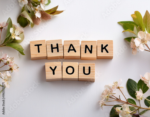 Obraz na płótnie The word THANK YOU written in wooden cubes on a white background with few flowers w salonie