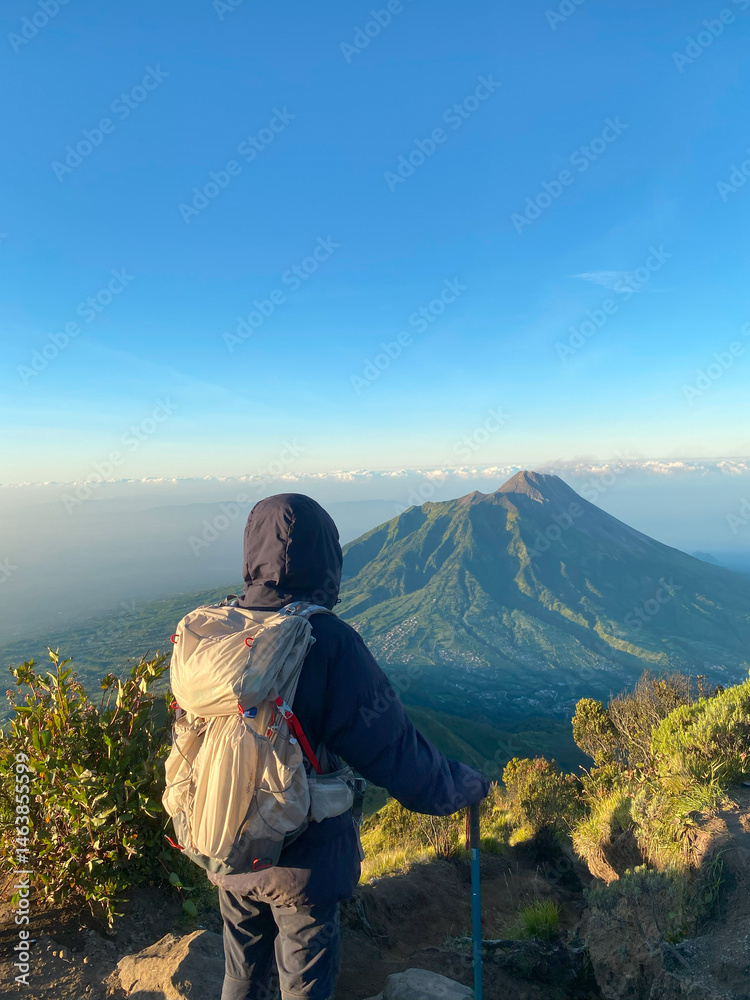 Fototapeta premium Man hiking Mount Merapi Morning View from Mount Merbabu – Scenic Volcanic Landscape in Indonesia