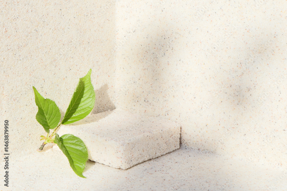 Rectangular stone podium against the background of a light stone wall and green sakura leaves. Cosmetic product display backdrop for luxury beauty. Minimalism style.