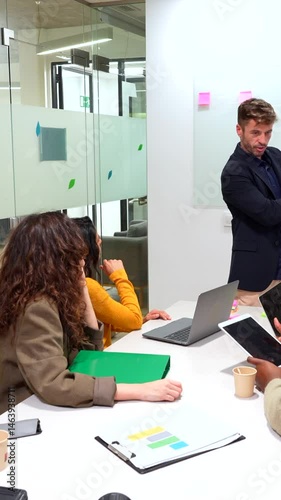Business professionals analyzing growth performance, sharing strategic insights during collaborative meeting in contemporary workspace with digital devices