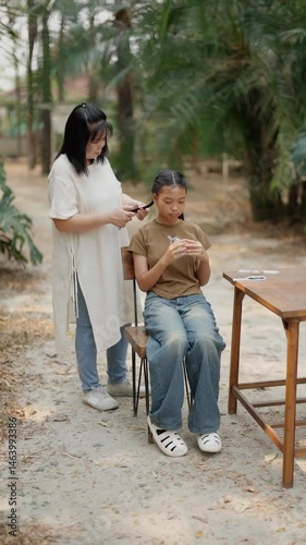 Asian mother braids her daughter's hair