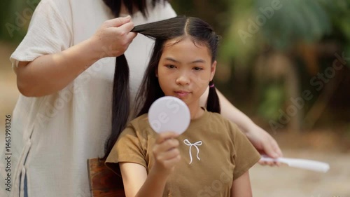 Asian mother braids her daughter's hair