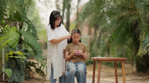 Asian mother braids her daughter's hair