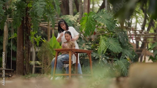 Asian mother braids her daughter's hair