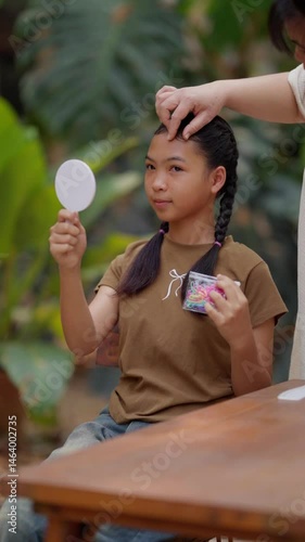 Asian mother braids her daughter's hair