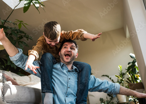 Father and son having fun indoors with the son sitting on the father's shoulders