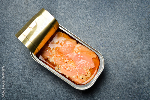 Canned of pickled salmon fillet set in a metal jar. Canned food in aluminum cans. On a gray concrete background.