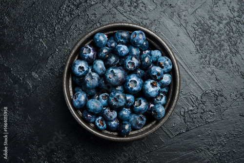 Close-up of blueberries in a bowl on a black slate table.