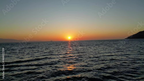 Close aerial footage of drone flying near the waterline – dramatic sunset atmosphere with gentle wave patterns photo