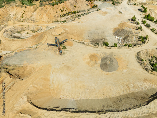 Obraz na płótnie Aerial drone view of sand or gravel quarry surrounded by forest and farmland with distant hills. Aerial Drone view shows an inactive or abandoned quarry embedded in a green landscape. w salonie
