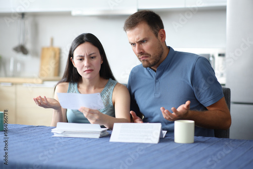 Angry interracial couple checking bank statement in a house