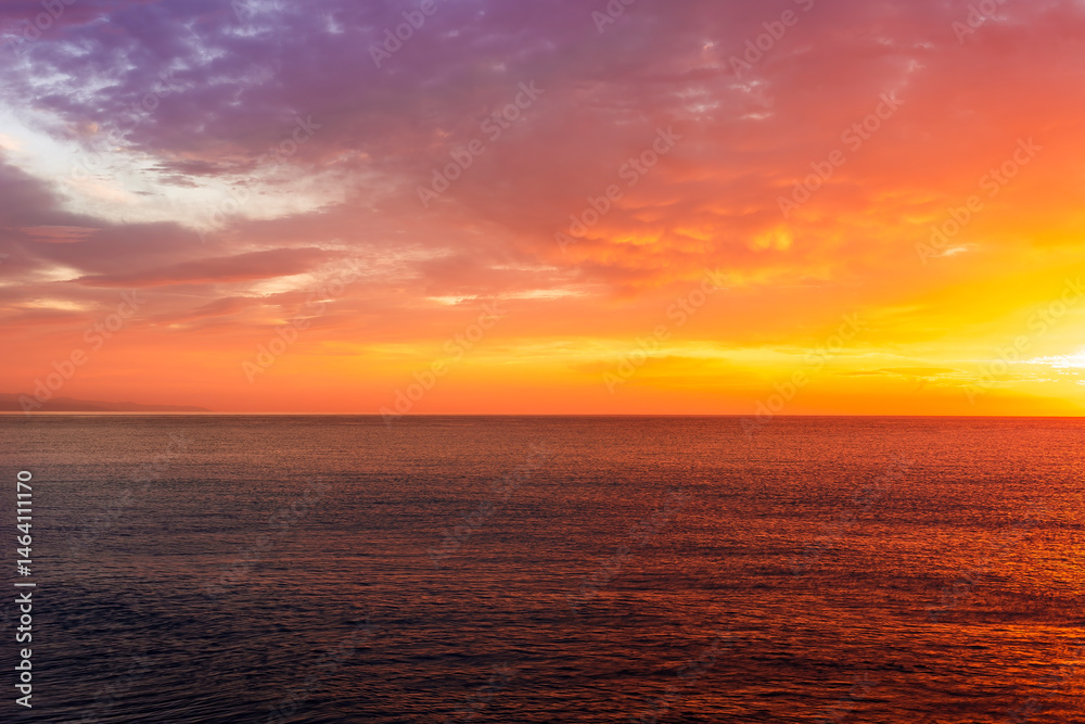 Obraz premium beautiful sunrise or sunset seascape with amazing calm sea water with waves and colorful amazing cloudy morning sky on background