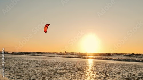 Surfer launches into air during sunset ride before landing with splash, Latvia