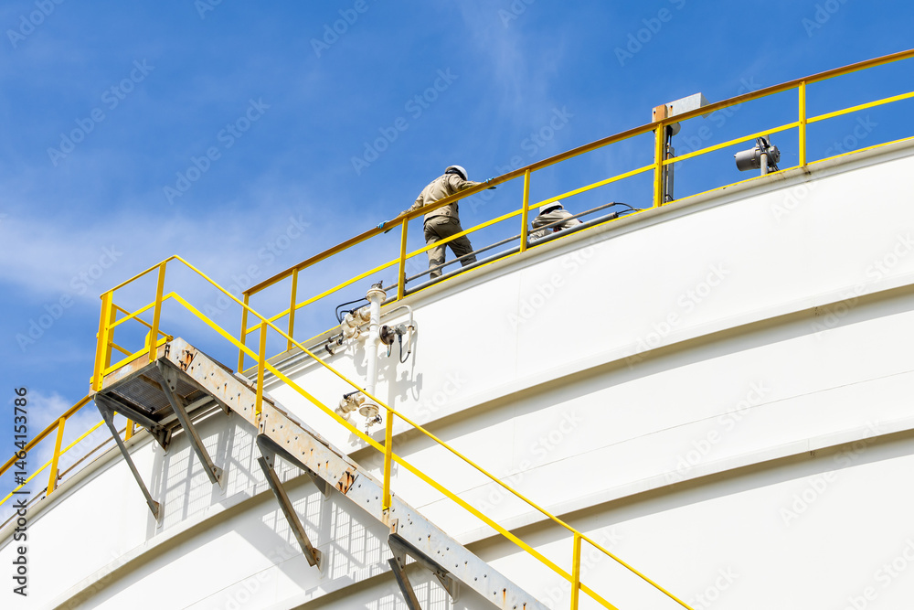 Industrial engineer work on top of crude oil storage tank, Two male worker inspection on the top of oil storage tank inspection visual check oil storage tank, Industrial worker on oil storage tank.