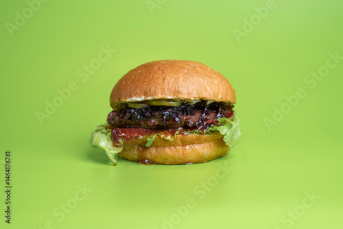Fresh burger with meat and salad on green background