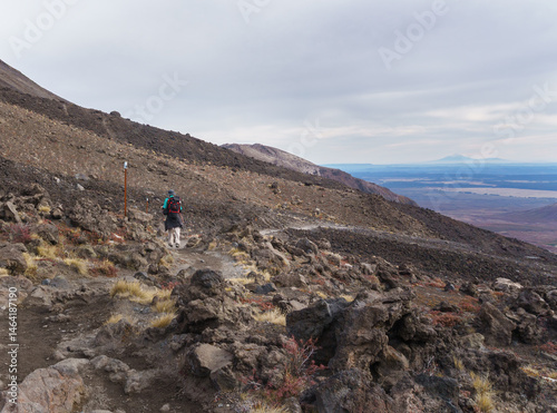 Obraz na płótnie Hiking winding volcanic scree at Tongariro Alpine crossing. Mt Taranaki in the far distance. Tongariro National Park. New Zealand. w salonie