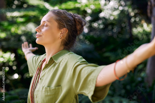 Woman breathing deeply with outstretched arms in the middle of nature