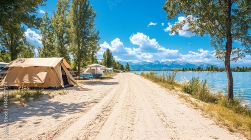 Lakeside camping scene with tents pitched on sandy beach path, under a vibrant summer sky and near water's edge