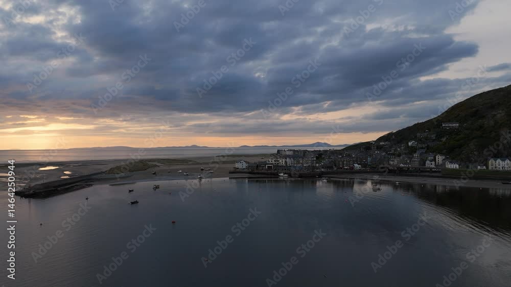 Drone flying on the river in front of Barmouth Harbor in North Wales during sunset under cloudy sky Drone flying on the river in front of Barmouth Harbor in North Wales during sunset under cloudy sky