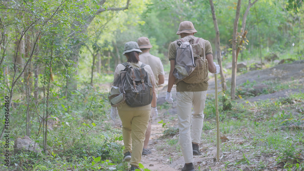 Naklejka premium Rear view of an eco-conscious family hiking through the forest with reusable bags for litter collection, promoting sustainable trekking, zero waste practices, and environmental responsibility.