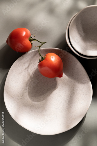Flat lay of gray monochrome plates and tomatoes. Culinary concept with space for text
