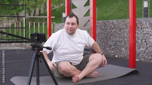 Fat man is trying to yoga outdoors, determined to lose weight and get back in shape.
