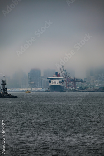 Luxury ocean liner cruiseship cruise ship Queen Mary docked at terminal in Brooklyn on grey rainy cloudy misty day after Transatlantic Crossing in New York City