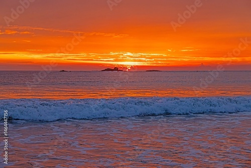 Sun setting over ocean at Ventura beach with soft waves and orange glow