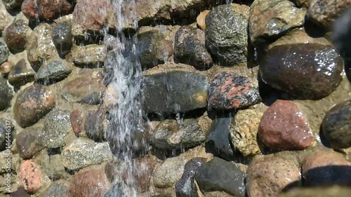 Waterfall over a stone wall. The water flows from above in a small stream.