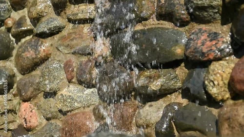 Waterfall over a stone wall. The water flows from above in a small stream.