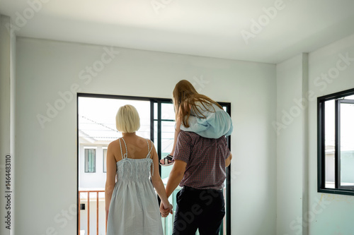Family inspects their new home together, looking out the doors and imagining the future in their fresh, empty space.