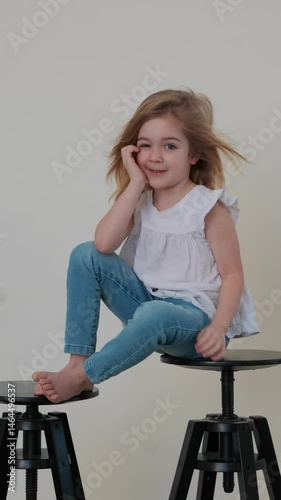 Child sits playfully on stool and enjoys a carefree moment at home