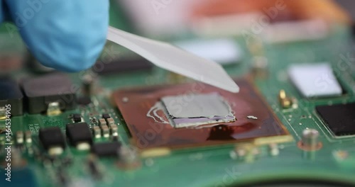Technician carefully applies thermal paste to computer processor at workplace. Employee ensures efficient heat dissipation and optimal performance