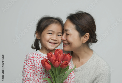 Tender portrait of mother and young daughter holding floral bouquet, sharing emotional smiles in a peaceful moment full of love and Mother's Day warmth.