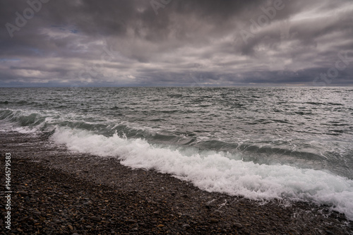 Obraz na płótnie Sun between dark storm clouds over ocean. Dramatic seascape. Clouds and rain flurry over sea. w salonie