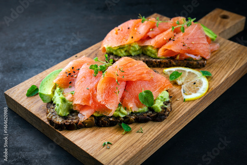 Bild auf Leinwand Pumpernickel bread sandwich snack with cured smoked Salmon and fresh avocado ser