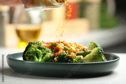 Fototapeta Naklejka Na Ścianę i Meble -  Woman adding spices to dish at table indoors, closeup