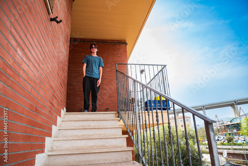 Caucasian teenage boy of 16-17 year old standiing at house stairs
