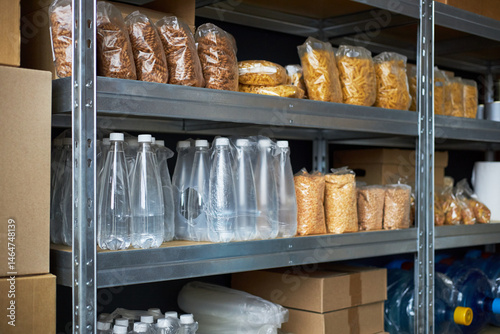 Slika na platnu Shelves filled with packaged food and bottled water in a storage area
