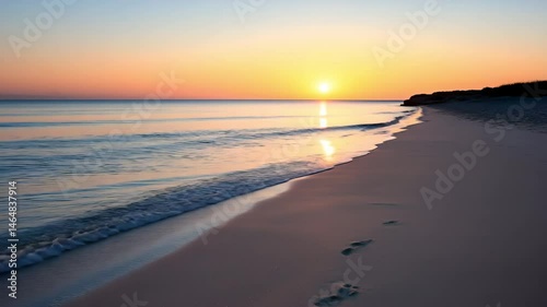 Wallpaper Mural The sun sets gently over a quiet beach with soft waves and footprints in the sand. concept of solitude and the passage of time. Torontodigital.ca