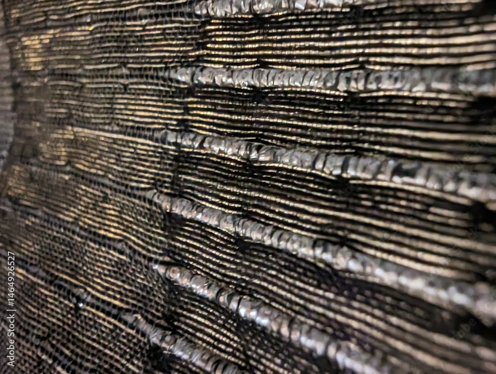 Fototapeta premium Close-up of textured black surface with grooves, abstract detail, black and gold tones, artistic composition