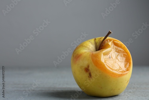 One rotten apple on grey wooden table, closeup. Space for text