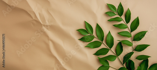 Green leaves on wrinkled beige paper background texture