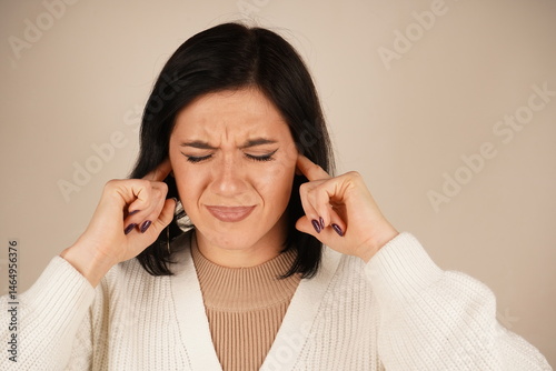 It's a natural reaction to overwhelming sound. The person covers their ears with their palms, attempting to block out unwanted noise. This gesture conveys a desire to avoid unpleasant information.