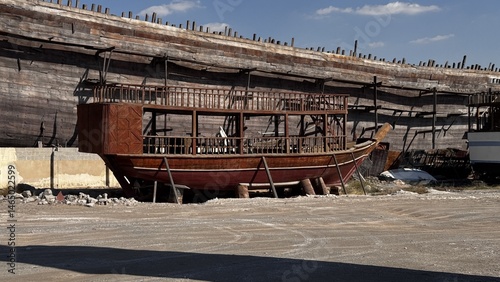 Tableau sur toile Weathered remains of an early 20th century wooden fishing boat lying abandoned near the shore under Dubai’s sunny sky