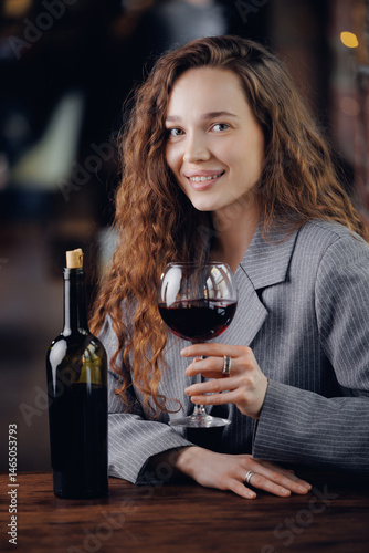 Portrait Caucasian female adult sommelier enjoying red wine in elegant setting