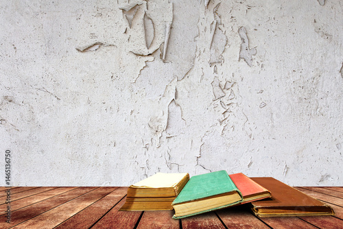 Aged book on wooden platform beside crack wall background.
