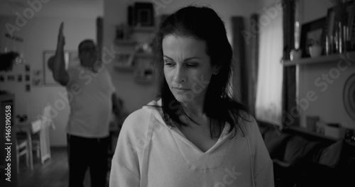 Woman turning her face away in black and white during heated argument, man in background gesturing emotionally, focus on tension and strained relationship dynamics