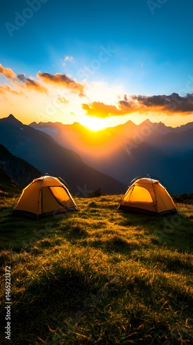 Two Yellow Tents on a Grassy Hilltop at Sunset with Mountain Range Silhouette under Starlit Sky